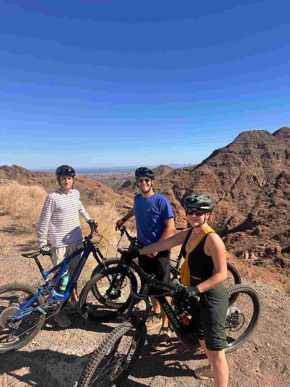 Three riders with electric mountain bikes on a desert ridge above the Sea of Cortez