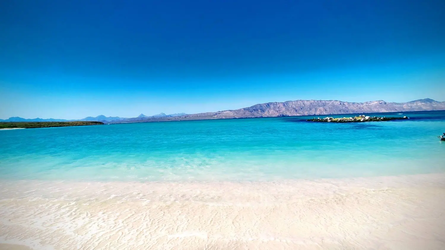 Clear turquoise shallows and white sand on an island beach near Loreto