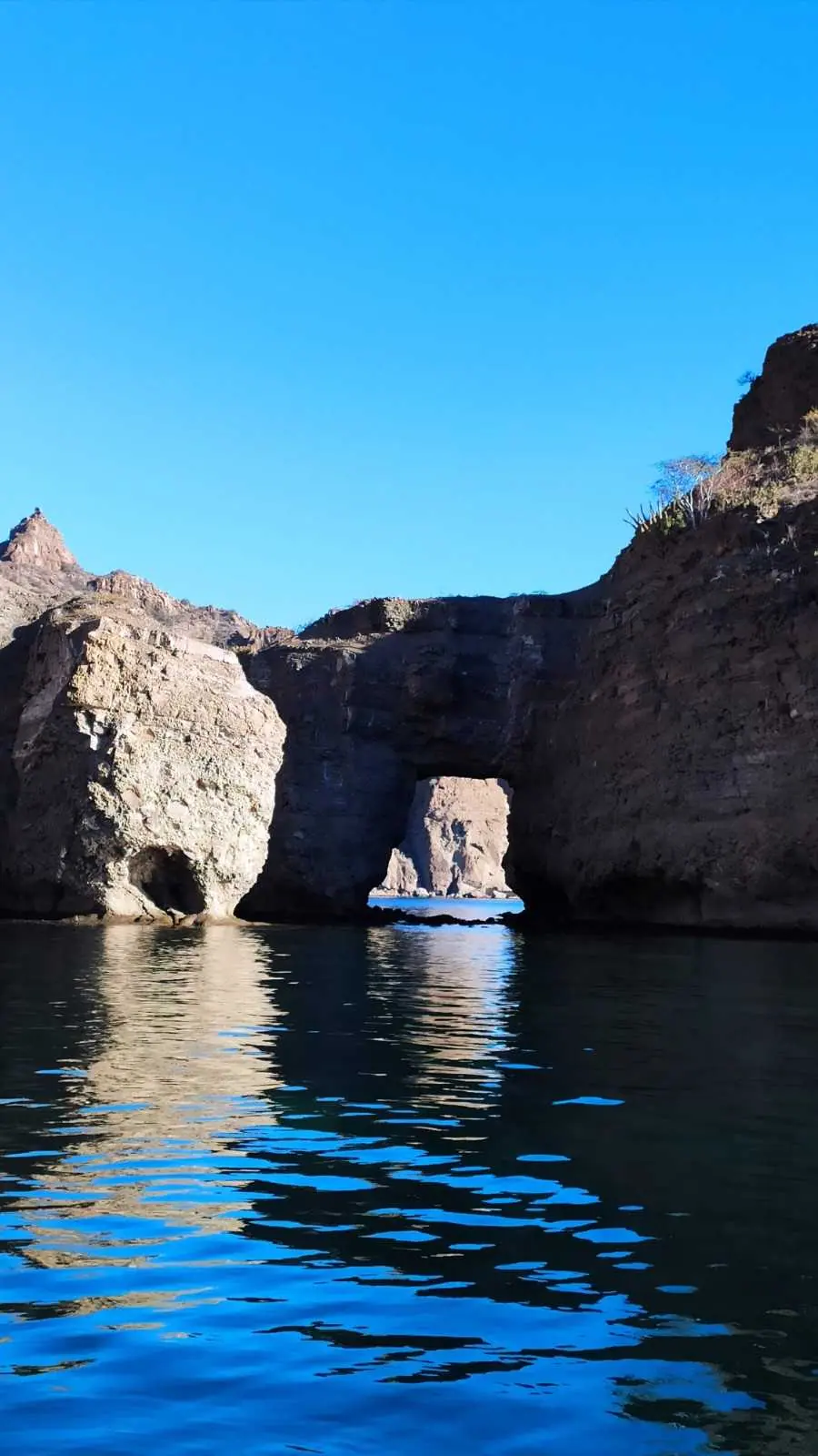A natural rock arch in the sea cliffs, seen from the water on an island boat tour