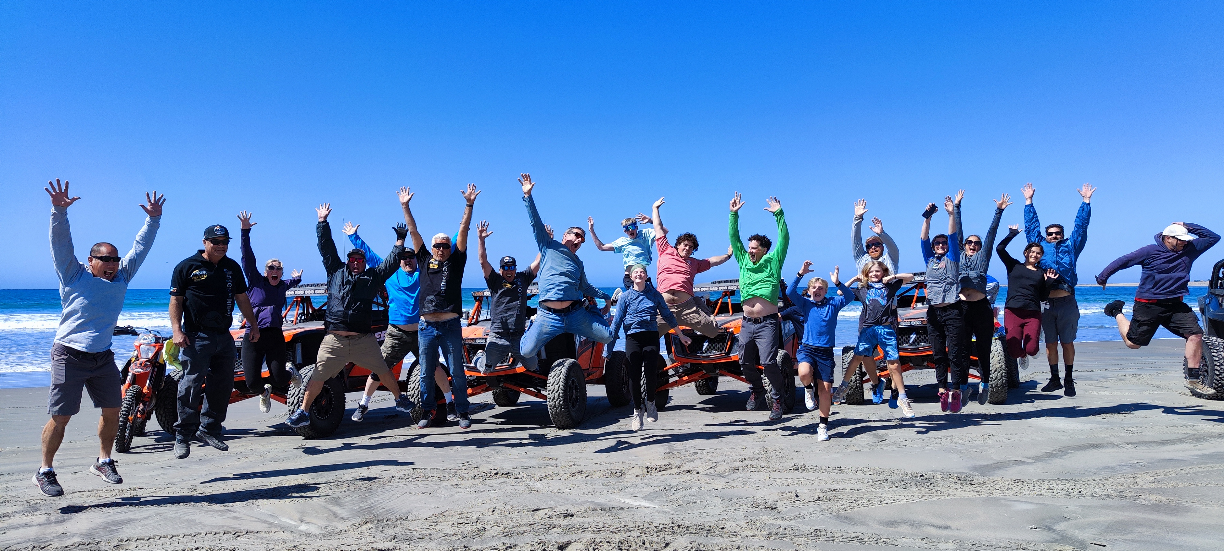 Convoy of UTVs crossing a sunlit Baja desert canyon